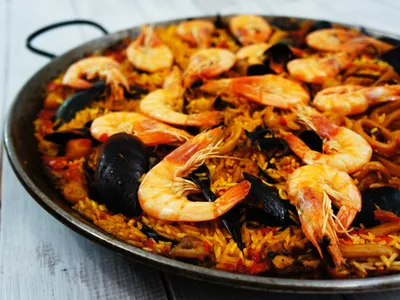 Close-up of a paella pan loaded with saffron rice, shrimp, and mussels