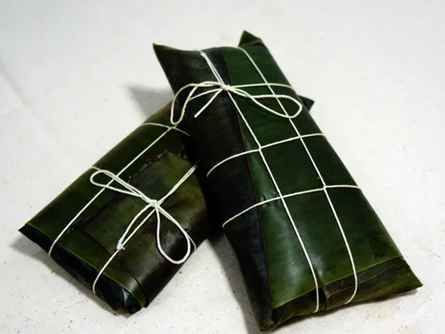 Two hallacas wrapped in plantain leaves and tied with cotton twine