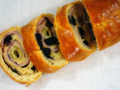 Sliced Pan de Jamon showing spiraled layers of ham, olives, and raisins inside golden bread