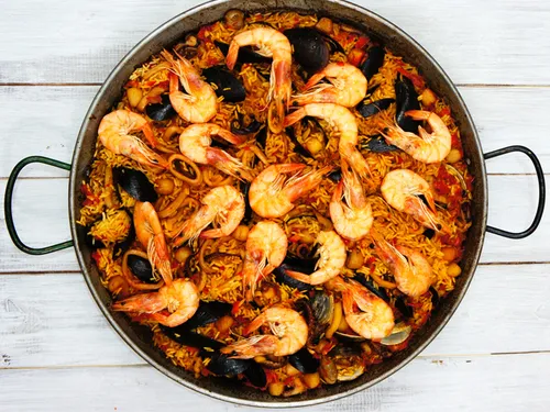 Overhead view of a full paella pan with shrimp, mussels, and rice