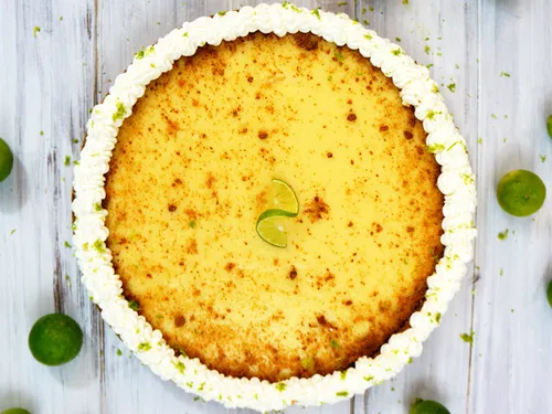 Overhead view of a whole key lime pie with a whipped cream border and lime slice garnish