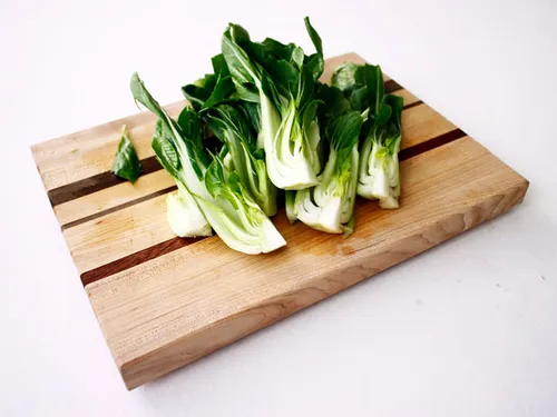 Baby bok choy sauteing in a pan with garlic and sesame oil