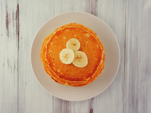 Overhead view of a buttermilk pancake topped with three banana slices